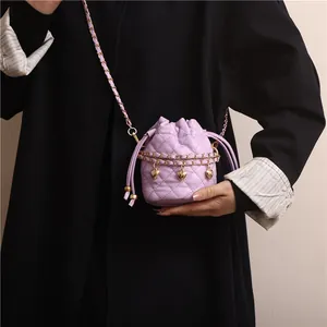 Detail view of lavender quilted bucket bag with gold heart charms and chain strap