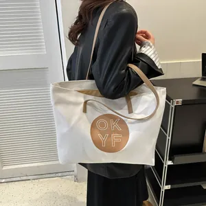 Detail of high-capacity white canvas tote bag with brown leather straps and OK YF logo