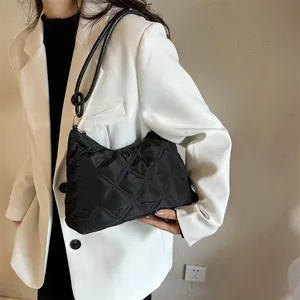 Detail of black quilted hobo bag with slim shoulder strap and golden zipper hardware