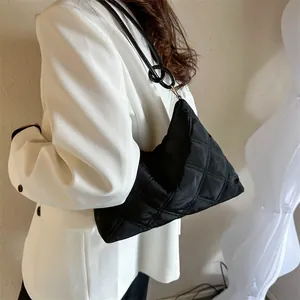 Detail of black quilted shoulder bag with metal ring buckle on the strap and nylon texture