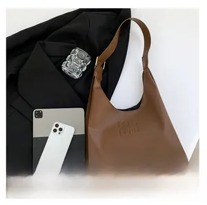 Detail of brown PU leather tote with embossed lettering and stylish wide strap