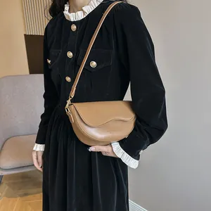 Sacoche marron en simili cuir portée par un mannequin en robe vintage noire
