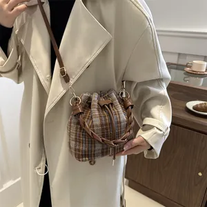 Detailed view of a vintage plaid bucket bag with woven handles and drawstring closure