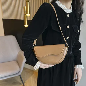 Détail du sac selle demi-cercle marron en cuir lisse avec rabat à courbe irrégulière