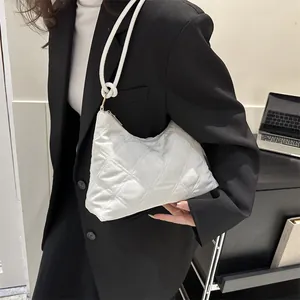 Detail of white quilted nylon underarm bag with elegant knotted strap and gold hardware