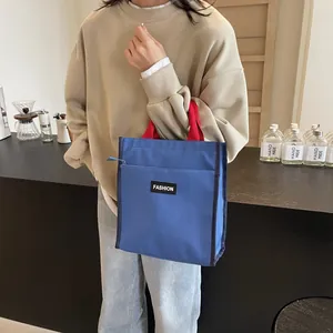 Minimalist navy blue lunch bag with red handles and zipper closure for office use