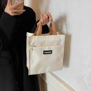 Minimalist beige commute lunch bag with brown handles and front zipper pocket