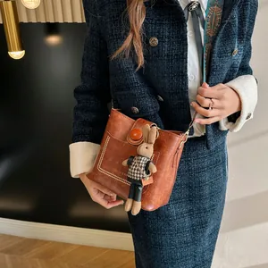 Detail view of brown vintage leather bucket bag with cute bunny charm and metal chain strap