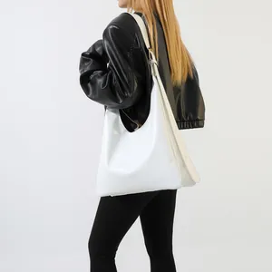 Detailed side view of a white leather tote bag styled on a model with wide strap