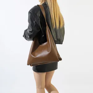 Detailed view of brown quilted PU leather crossbody bag with side letter engraving