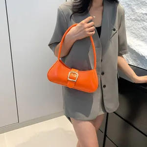 Borsa a spalla baguette arancione brillante con fibbia d'argento indossata da una modella
