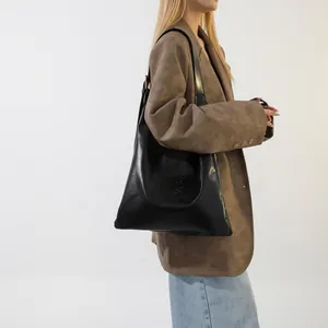 Detailed view of black quilted leather tote bag with embossed letters on a model