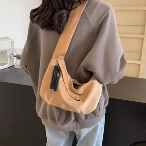 Rear view of a camel nylon tote bag with wide shoulder strap worn by a model