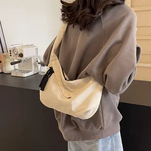 Detail of a beige nylon crescent hobo bag with a woven zipper pull for casual daily use