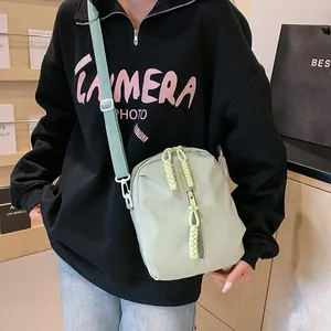 Detalle de bolso bandolera verde menta con cremallera trenzada amarilla visto en modelo