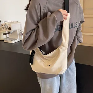 Cream half-moon tote bag with black strap and woven tassel for daily casual wear
