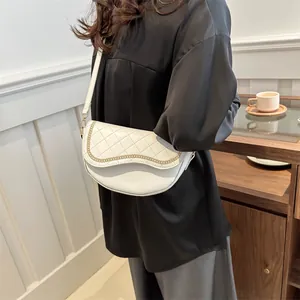 Gros plan d'un sac selle blanc matelassé avec chaîne dorée et bandoulière en cuir