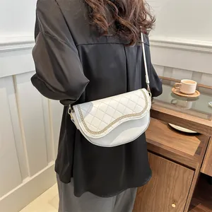 Gros plan du sac selle blanc matelassé avec une chaîne dorée élégante et bandoulière cuir