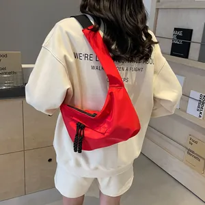 Rear view of a model wearing a bright red crescent nylon crossbody bag with black strap