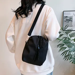 Detalle de bandolera de nailon negro con cremallera trenzada y gancho de plástico blanco