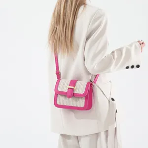 Detail of woven straw texture and bright pink leather trim on chic crossbody bag