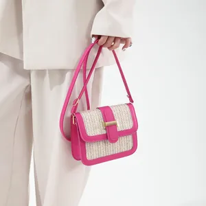 Detail of woven straw crossbody bag with fuchsia leather trim and golden H-clasp