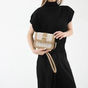 Close-up of woven raffia handbag with khaki leather trim and golden H-shaped clasp