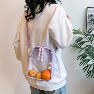 Detalle de bolso bandolera transparente morado con correa ajustable y cierre de cremallera