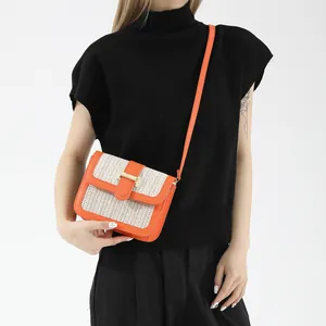 Close-up of contrast crossbody bag with orange leather trim and woven straw texture