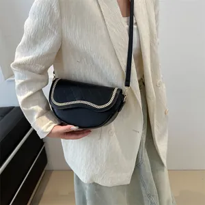 Détail du sac selle noir avec matelassage en losanges et chaîne dorée sur mannequin
