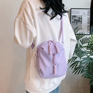Bolso bandolera de nailon violeta claro con tiradores de cuerda trenzada usado por una modelo
