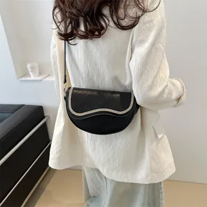 Détail du sac selle matelassé noir avec chaîne dorée et bandoulière en cuir souple