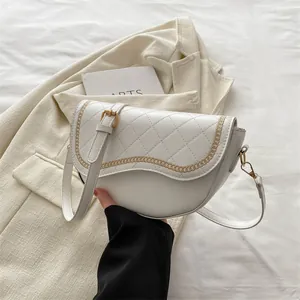Détail du sac selle matelassé avec motif chaîne dorée et bandoulière réglable
