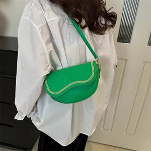 Sacoche selle matelassée verte avec chaîne dorée, portée par un mannequin en intérieur