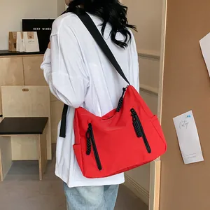 Sac fourre-tout rouge en nylon avec fermetures noires et sangle ajustable sur mannequin