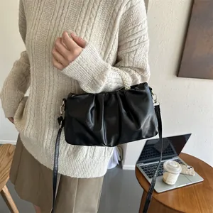 Détail du sac nuage noir plissé avec poignée en perles et bandoulière sur table
