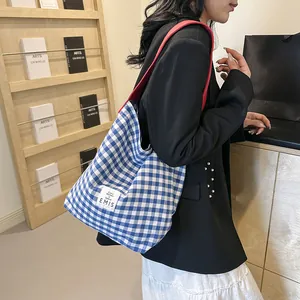 Detail of blue checkered canvas tote bag with red strap showing ample storage capacity