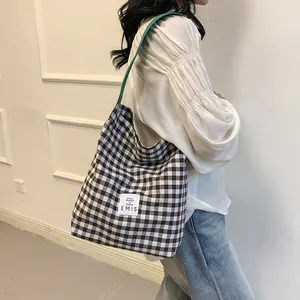 Detail view of the EMIS logo patch on a brown checkered canvas tote bag with green strap