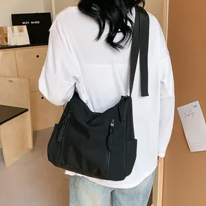 Détail du sac bandoulière en nylon noir avec doubles zips parallèles et tirettes tressées