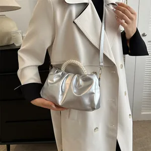 Détail du sac nuage argenté plissé avec poignée en perles sur un manteau blanc chic