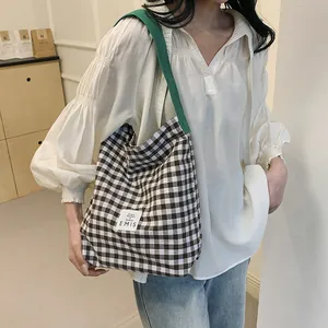 Detail of checkered canvas tote bag with green shoulder strap and EMIS textile label