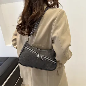 Detail of dark gray denim underarm bag with silver zippers and contrast white stitching