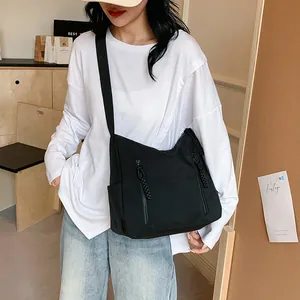 Détail du sac bandoulière en nylon noir avec fermetures éclair verticales et cordons