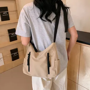 Détail du sac cabas en nylon kaki avec fermetures noires et poches latérales sur étagère