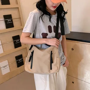 Détail du cabas en nylon beige avec double fermeture éclair frontale et bandoulière