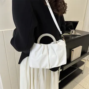 Élégant sac nuage plissé blanc avec poignée en perles porté par un mannequin dans un bureau