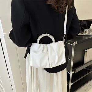Détails du sac nuage blanc avec poignée en perles et design plissé porté par un modèle