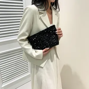 Detail of a chic black sequined clutch bag held by a model against a minimalist background