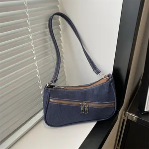 Detailed macro view of dark denim shoulder bag with white contrast stitching and zippers