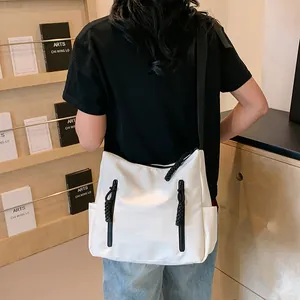 Détail du sac cabas en nylon blanc avec fermetures noires et large bandoulière réglable